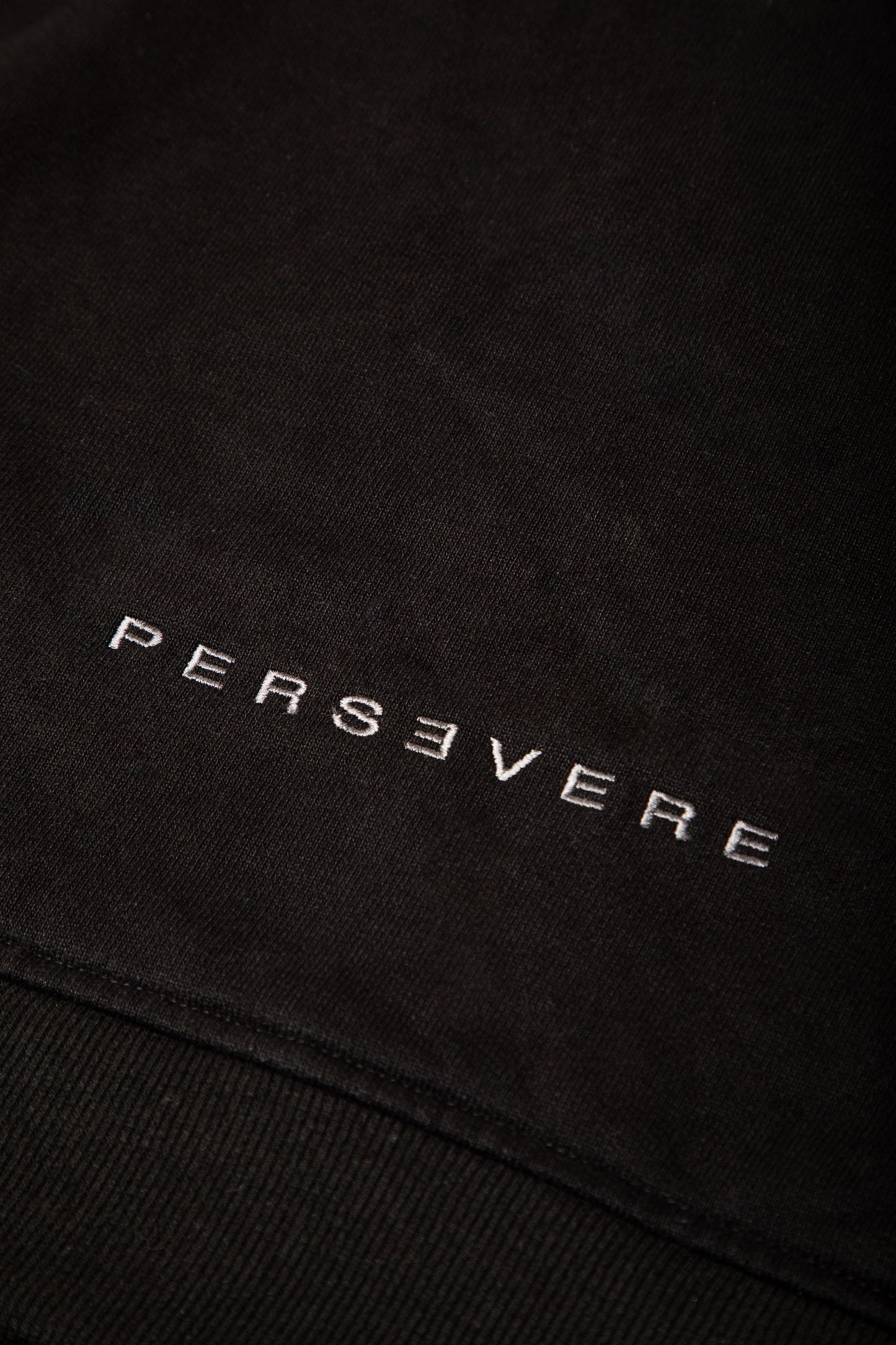 Black fabric with 'PERSEVERE' embroidered in gray