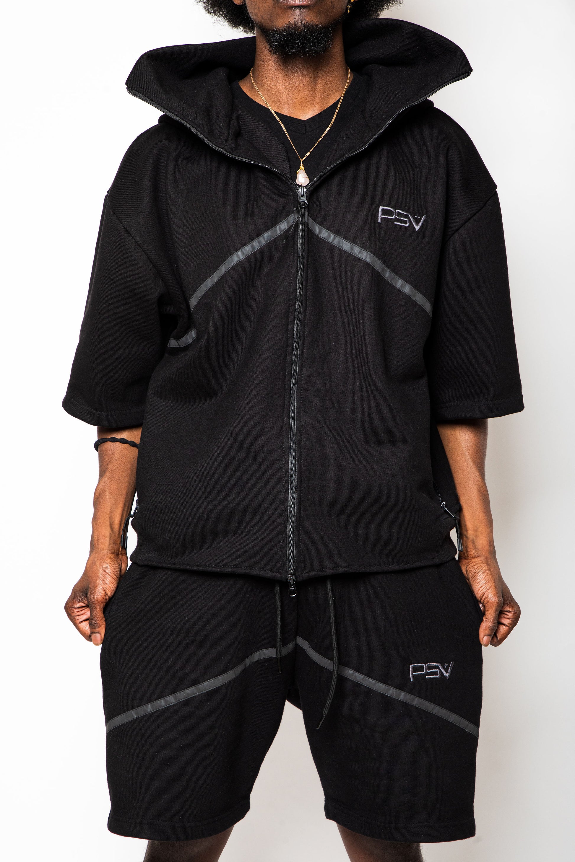 Person wearing a black hoodie and shorts set with 'PSV' branding on a white background