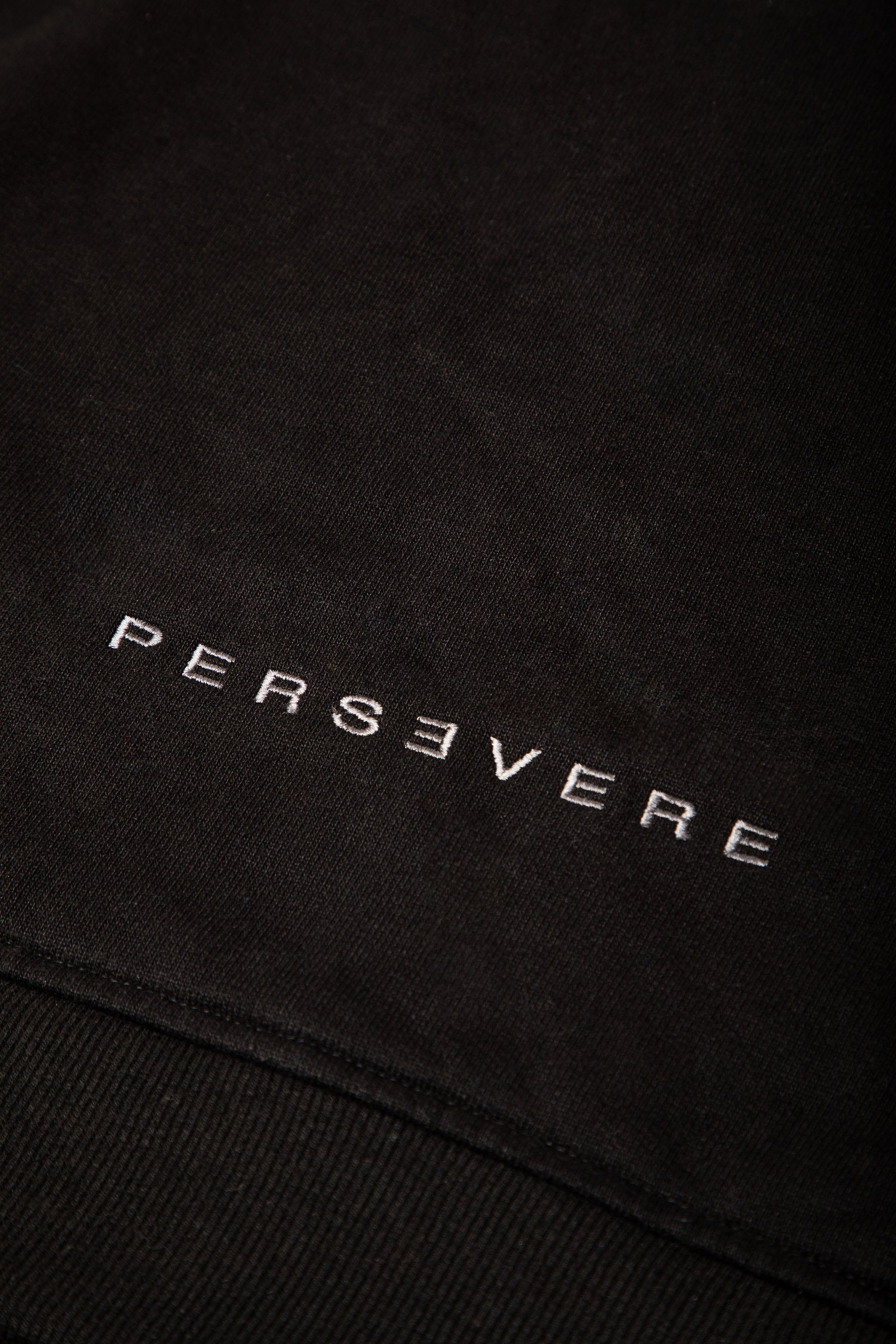 Black fabric with 'PERSEVERE' embroidered in gray
