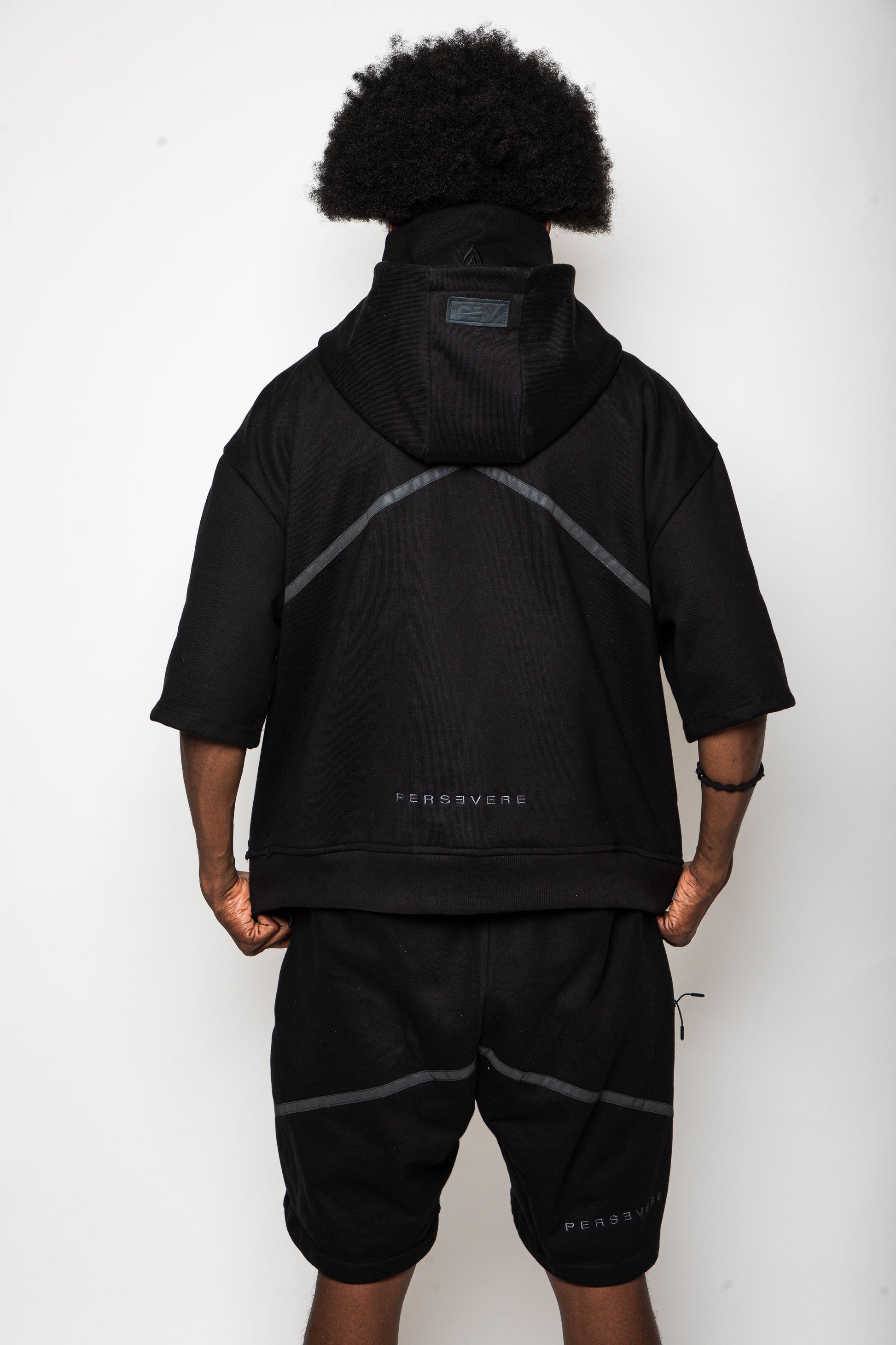 Person wearing a black hoodie and shorts set with 'PERSEVERE' branding on a white background